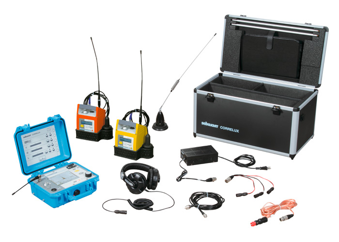 A portable radio communication kit with a blue control unit, two walkie-talkies (yellow and orange), black headset, various cables, antennas, power adapter, and an open black equipment case.