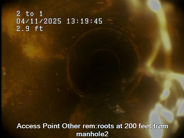 View from inside a sewer pipe with a timestamp and measurements overlay. Text at the bottom reads: "Access Point Other rem: roots at 200 feet from manhole2.