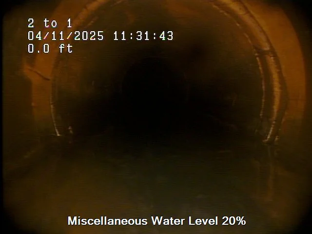 View inside a dark, cylindrical tunnel with some water at the bottom. Text overlay shows "04/11/2025 11:31:43," water level at "0.0 ft," and a caption reads "Miscellaneous Water Level 20%.